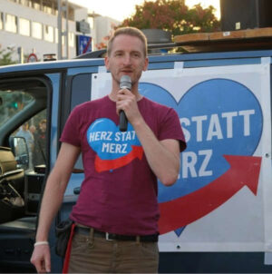 T-Shirt "Herz statt Merz" in weinrot getragen von Marcus Fuchs auf der Montagsdemo in Dresden